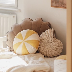 Peut inclure: Une tête d'éléphant blanche et dorée avec une couronne, accrochée à un mur blanc. Un oreiller rayé brun et blanc et un oreiller en crochet crème sont sur un lit blanc avec une couverture blanche.