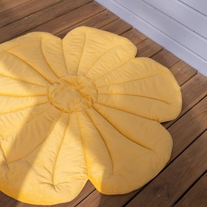 May include: A yellow flower-shaped play mat with a quilted design. The mat is made of soft fabric and is ideal for babies and toddlers to play on.