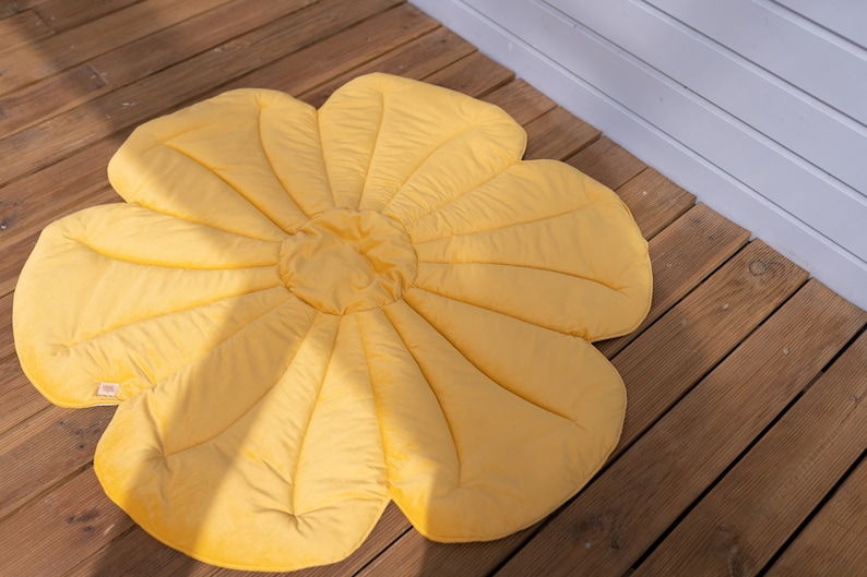 May include: A yellow flower-shaped play mat with a quilted design. The mat is made of soft fabric and is ideal for babies and toddlers to play on.