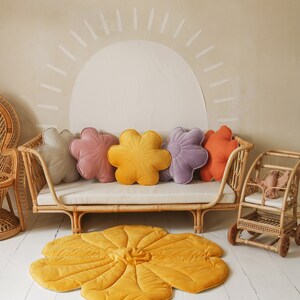May include: A yellow flower-shaped play mat with a rattan daybed and five flower-shaped cushions in various colours, including pink, purple, and orange.