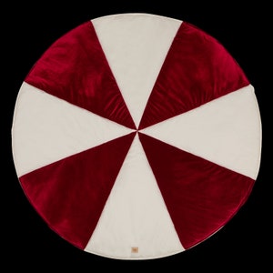 May include: A round, red and white play mat with a candy cane design. The mat is made of soft, plush fabric and is ideal for babies and toddlers.