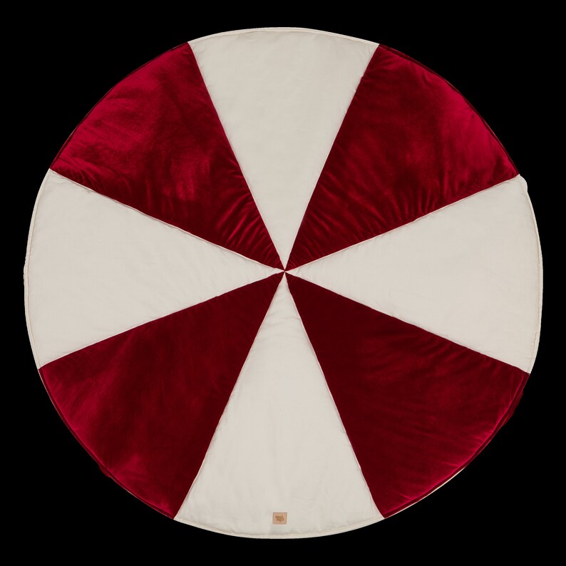 May include: A round, red and white play mat with a candy cane design. The mat is made of soft, plush fabric and is ideal for babies and toddlers.