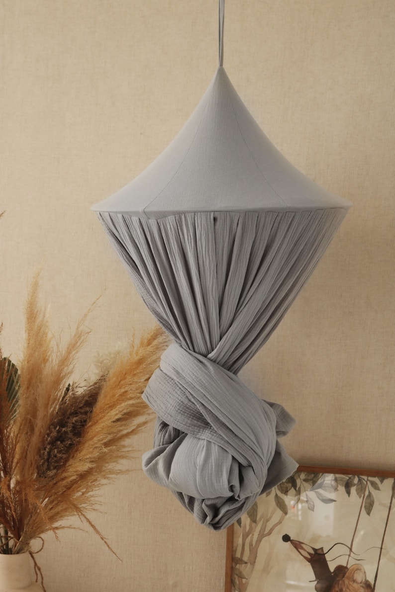 May include: A gray cotton canopy hanging from the ceiling. The canopy is gathered at the bottom and tied in a knot.