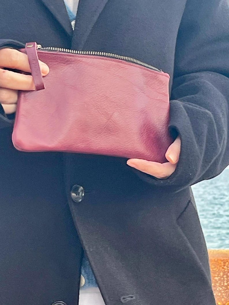 May include: A burgundy leather zippered pouch with a small leather strap.