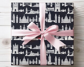 May include: A wrapped gift with a navy blue background featuring a white London cityscape pattern. The gift is tied with a light pink satin ribbon and bow, presented on a white wooden surface.