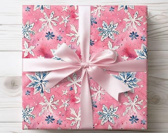 May include: A pink gift box with a white and blue snowflake pattern wrapped with a pink satin ribbon.