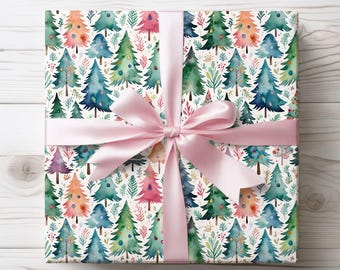 May include: A wrapped gift with watercolor Christmas tree pattern wrapping paper. The paper features colorful trees in shades of green, blue, pink, and orange on a white background. A light pink satin ribbon is tied in a bow around the gift.