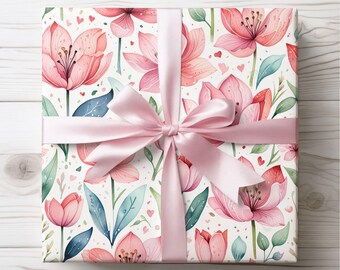 May include: A gift box wrapped in white paper with a pink floral pattern. The box is tied with a pink satin ribbon.