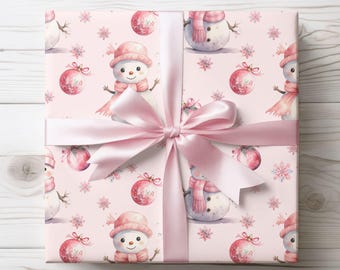 May include: Pink gift wrapping paper with a repeating pattern of snowmen, snowflakes, and pink baubles. The paper is tied with a pink satin ribbon.