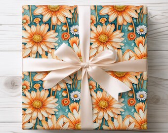 May include: A wrapped gift with a floral pattern featuring large orange daisies with yellow centres and smaller white daisies on a teal background. The gift is tied with a cream-coloured satin ribbon and bow, ideal for a special occasion.
