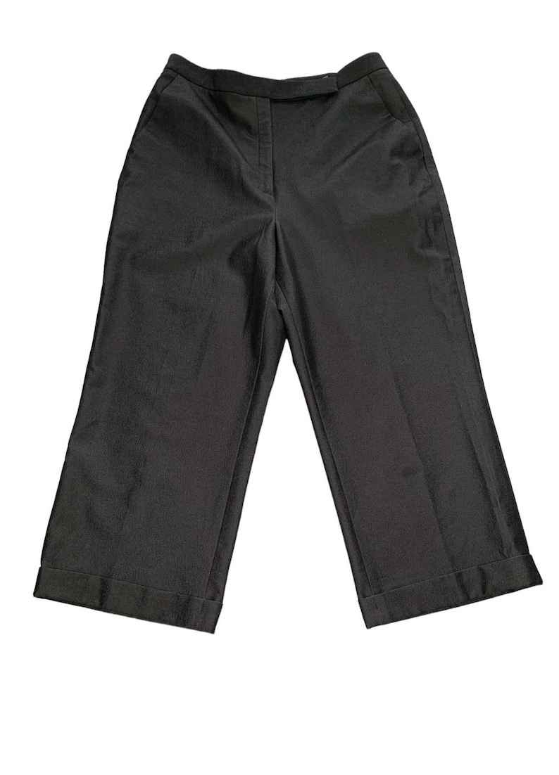 Pode incluir: Cal&ccedil;as cinza escuro de perna larga com um corte sob medida. As cal&ccedil;as apresentam cintura alta, bolsos frontais e bainhas com punho. O tecido tem um brilho sutil, sugerindo um estilo formal. Uma pe&ccedil;a de vestu&aacute;rio cl&aacute;ssica e vers&aacute;til.