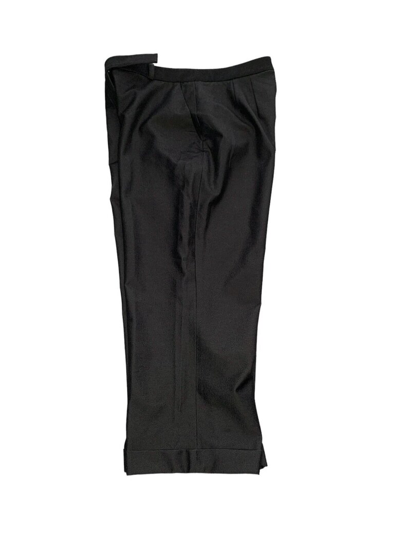 Pode incluir: Cal&ccedil;as pretas de fato com bainha dobrada. As cal&ccedil;as t&ecirc;m um design cl&aacute;ssico com perna reta e corte sob medida. O tecido parece ser um material preto liso e uniforme. As cal&ccedil;as est&atilde;o dobradas ao meio.