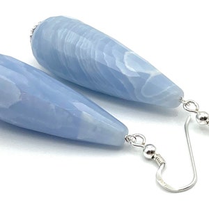 Peut inclure: Une paire de boucles d'oreilles pendantes avec des pierres en agate bleu clair en forme de larme et des crochets argentés.