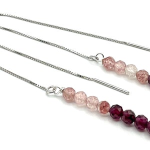 Peut inclure: Une paire de boucles d'oreilles en chaîne argentée avec un dégradé de perles roses et violettes. Les perles sont facettées et ont un léger éclat.