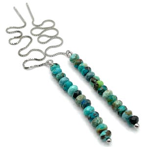 May include: Threader earrings with faceted turquoise beads and fine silver chains. The turquoise beads are in shades of blue, green, and brown. The earrings have a simple, elegant design, suitable for everyday wear.