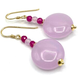 Può includere: Un paio di orecchini pendenti con perline rosa e fucsia e una grande pietra rosa.