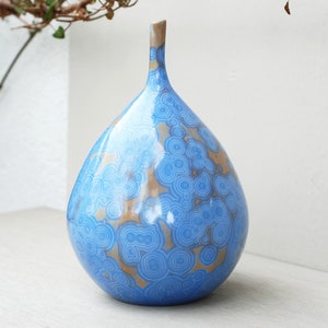 Può includere: Un vaso in ceramica blu e marrone con un motivo a spirale. Il vaso ha un corpo rotondo a forma di pera e un collo stretto.