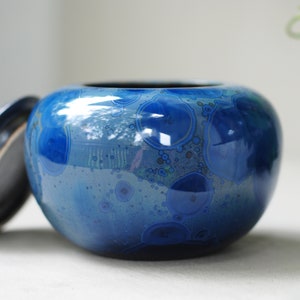 K&ouml;nnte beinhalten: Eine blaue Keramikdose mit Deckel. Die Dose hat ein wirbelndes Muster aus Blau und Wei&szlig;.