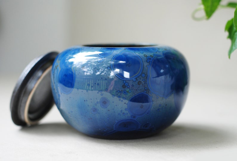 K&ouml;nnte beinhalten: Eine blaue Keramikdose mit Deckel. Die Dose hat ein wirbelndes Muster aus Blau und Wei&szlig;.