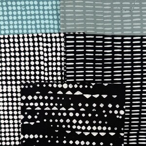 May include: A patchwork textile with various patterns. The top left section features small, evenly spaced blue dots. The top right section has white dashes on a gray background. The bottom sections display black and white dot and dash patterns.