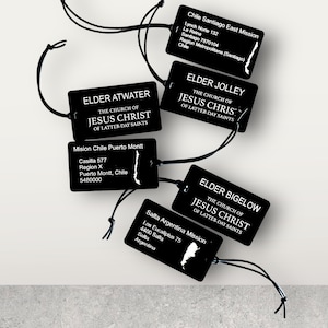 May include: Black and white name tags with the text "The Church of Jesus Christ of Latter-day Saints" and the names of different missionaries. The tags are shaped like the outline of Chile and Argentina.