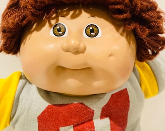 Muñeca Cabbage Patch Boy de pelo castaño, 1986, ropa original, detalle de hoyuelos.