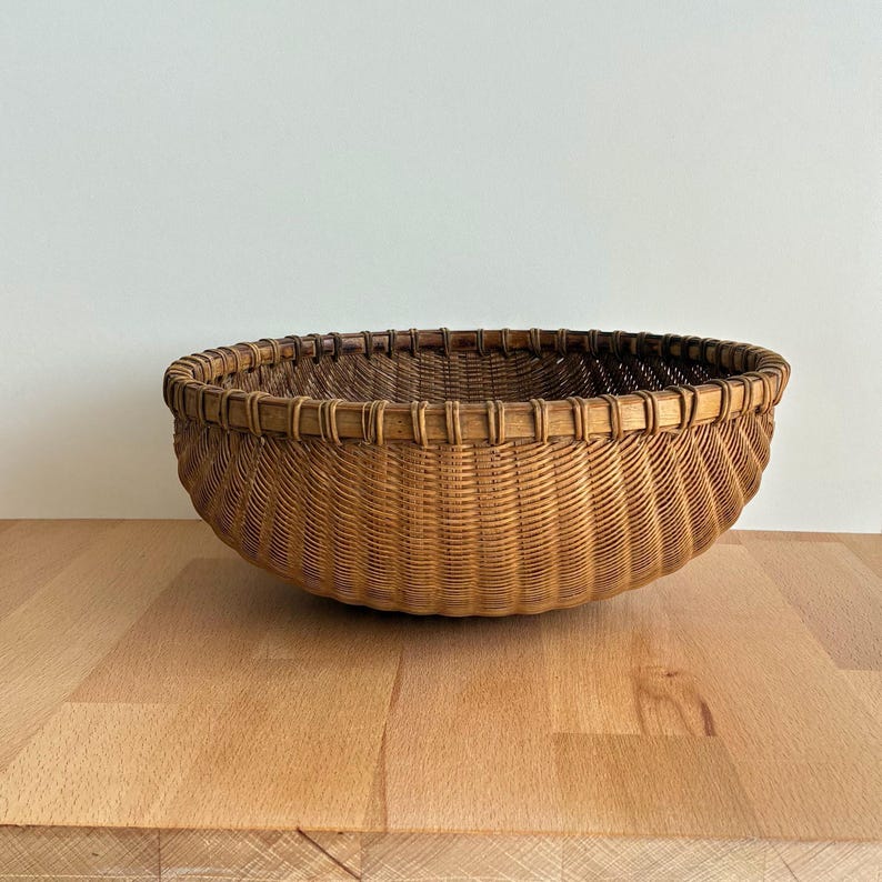 Pu&ograve; includere: Un cesto rotondo intrecciato di colore marrone naturale. Il cesto presenta un design ampio e aperto con un bordo robusto e una superficie strutturata. &Egrave; realizzato in materiale tessuto, adatto per riporre o esporre. Diametro di circa 30 cm.