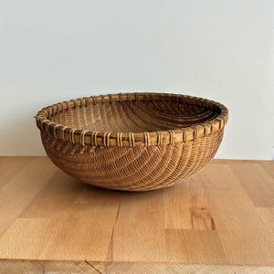 Pu&ograve; includere: Un cesto rotondo intrecciato di colore marrone naturale. Il cesto presenta un design ampio e aperto con un bordo robusto e una superficie strutturata. Il cesto &egrave; realizzato in materiale intrecciato ed &egrave; adatto per la conservazione o l'esposizione.