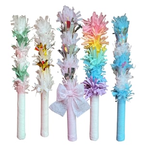 May include: A collection of five colorful party favors. Each favor has a white cylindrical base wrapped in paper, topped with a cluster of fringed paper in various colors, including green, pink, silver, rainbow, and blue. One favor has a pink bow.