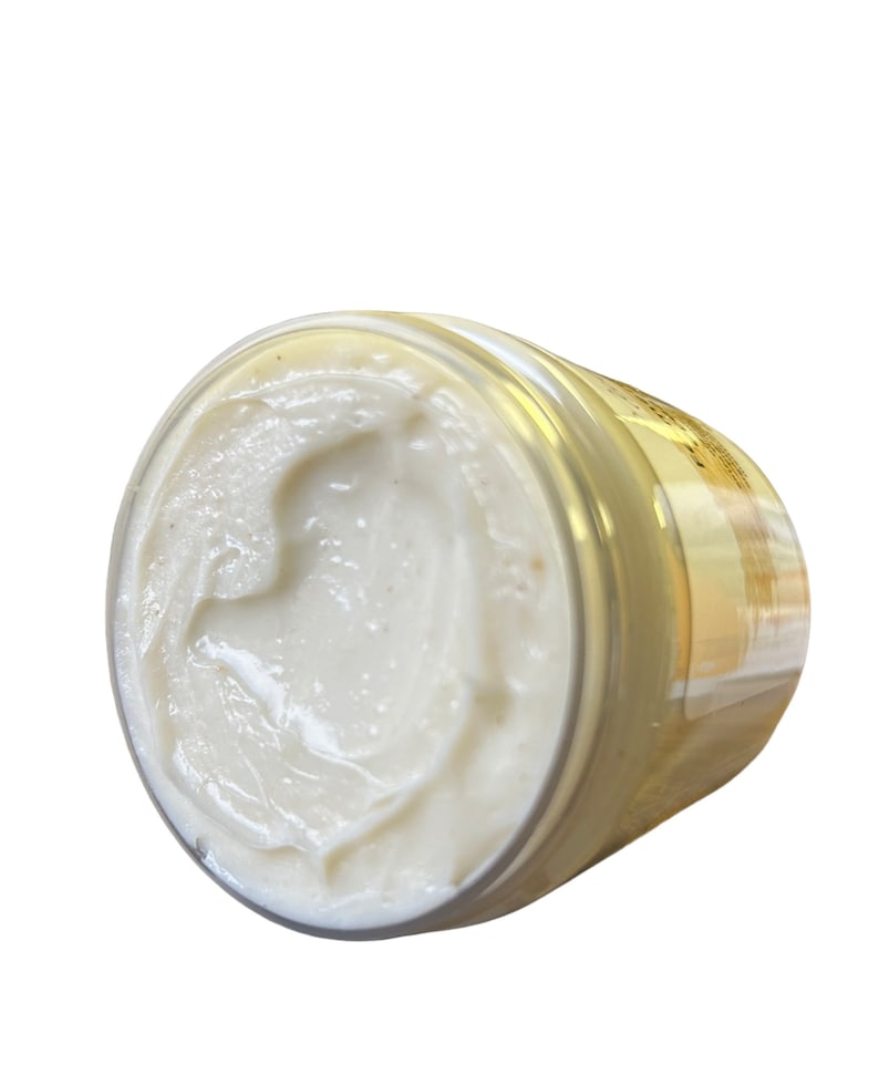May include: A white jar of body butter with a gold lid. The jar is filled with a thick, creamy product.