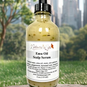 May include: A clear glass bottle with a black dropper top, labeled "Nature's Ego Emu Oil Scalp Serum". The bottle contains a light yellow liquid and is sitting on a wooden surface. The label lists the ingredients, directions for use, and contact information. The bottle is 4 ounces (119 ml).