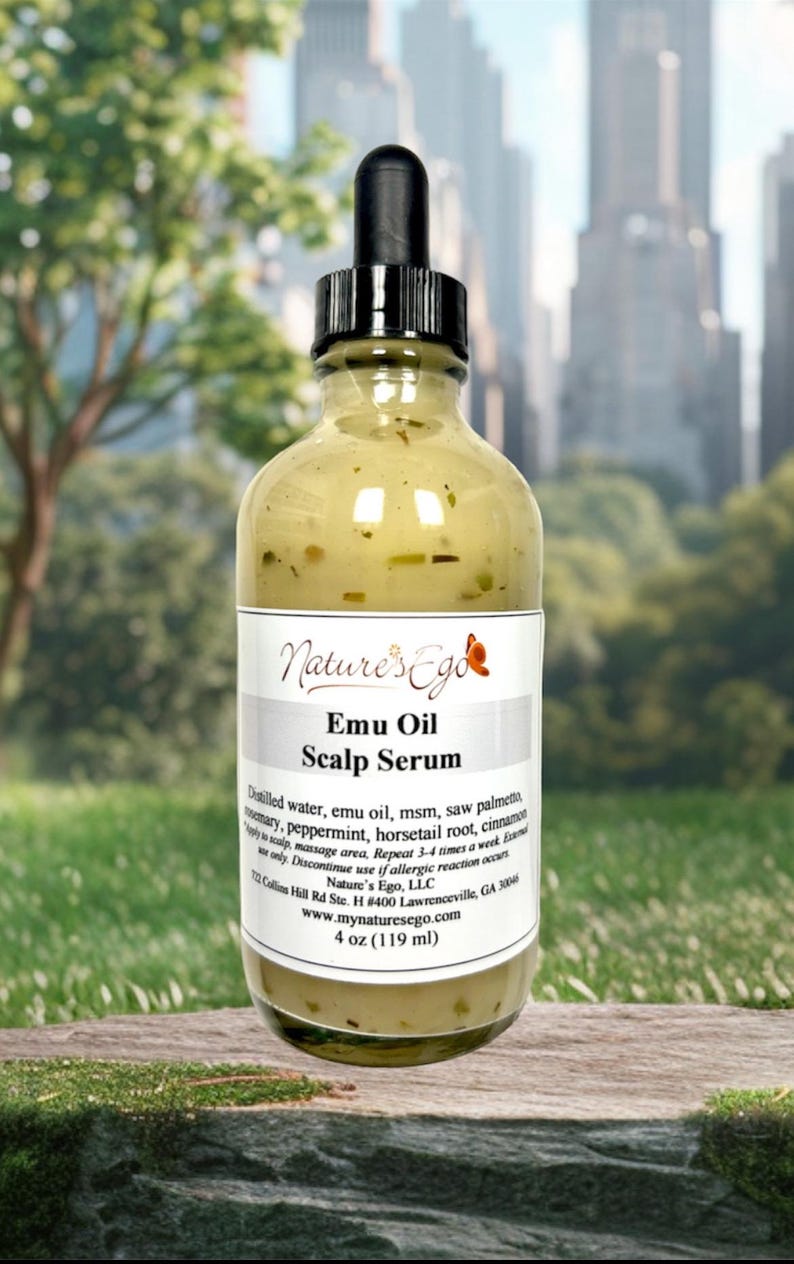 May include: A clear glass bottle with a black dropper top, labeled "Nature's Ego Emu Oil Scalp Serum". The bottle contains a light yellow liquid and is sitting on a wooden surface. The label lists the ingredients, directions for use, and contact information. The bottle is 4 ounces (119 ml).