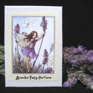 May include: A white box with a lavender fairy perfume label. The label features a fairy with wings holding a lavender flower, a butterfly, and the text "Lavender Fairy Perfume".