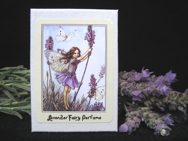 May include: A white box with a lavender fairy perfume label. The label features a fairy with wings holding a lavender flower, a butterfly, and the text "Lavender Fairy Perfume".