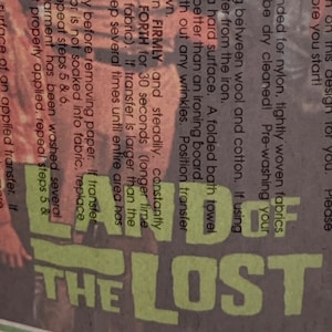 May include: Close-up of a green and white iron-on transfer sheet with instructions for applying the transfer to fabric. The sheet features the text "THE LOST" in large, bold letters.