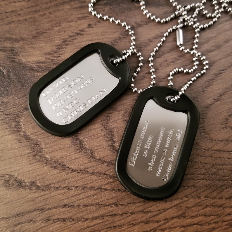 May include: Two black dog tags on a silver chain. The top tag reads "DAVID JAMESON 1934-1993 O NEC CHRISTIAN". The bottom tag reads "Distance means so little when someone means so much. Come home safe."