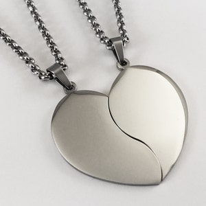 Puede incluir: Dos collares de plata con colgantes en forma de coraz&oacute;n a juego que encajan. Los colgantes son lisos y brillantes.