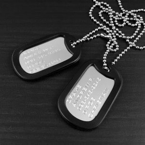 May include: Two black dog tags with silver chains. The top tag reads "Dad & Nate" and the bottom tag reads "Jake Andrew 588-248-5428 O. Pos. Christian".