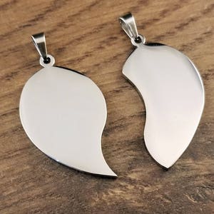 Puede incluir: Dos collares colgantes de plata en forma de coraz&oacute;n, cada mitad del coraz&oacute;n est&aacute; separada. Los colgantes son lisos y brillantes.