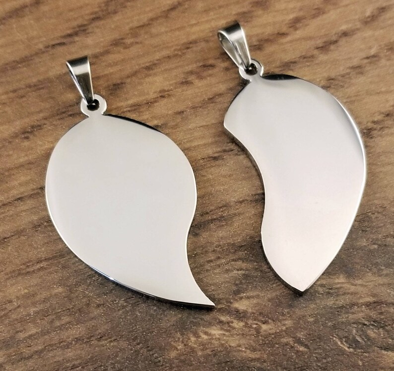 Puede incluir: Dos collares colgantes de plata en forma de coraz&oacute;n, cada mitad del coraz&oacute;n est&aacute; separada. Los colgantes son lisos y brillantes.