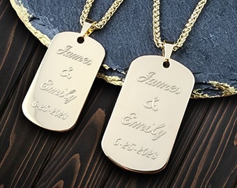 May include: Two gold dog tag necklaces with the names "James & Emily" and the date "6-25-2023" engraved on them.