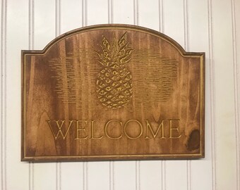 Welcome sign with gold pineapple motif.