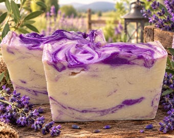 May include: Two rectangular bars of handcrafted soap featuring a creamy off-white base with vibrant purple swirls throughout. The soap bars have a smooth, solid texture and are displayed with sprigs of fresh lavender flowers nearby.