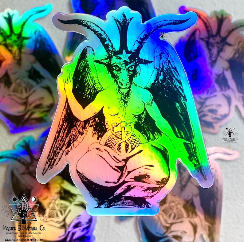 May include: A holographic sticker featuring a black and white illustration of a goat-headed figure with wings, sitting on a throne. The figure has a pentagram on its forehead and is holding a snake in its hands. The sticker has a rainbow iridescent finish.