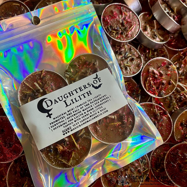 May include: Three brown tea light candles with herbs and glitter. The candles are packaged in a holographic bag with the text "Daughters of Lilith" and a description of the candles' magickal properties.