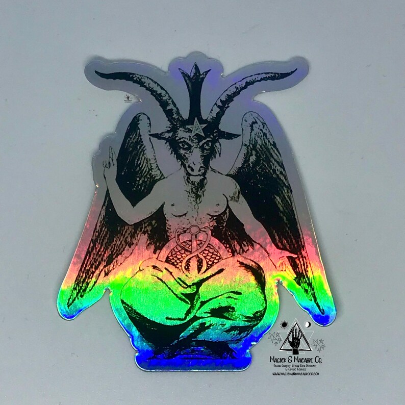 May include: A holographic sticker featuring a black and white illustration of a winged demon with horns and a pentagram on its forehead. The demon is sitting in a meditative pose with its hands resting on its knees. The sticker has a rainbow iridescent background.