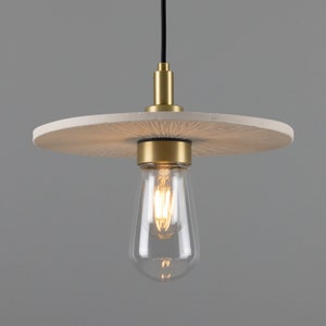May include: A white, round, textured ceiling light fixture with a gold metal base and a clear glass light bulb.