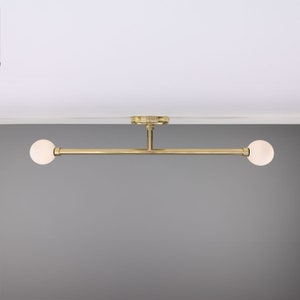 May include: A gold ceiling light fixture with two white globe-shaped shades.