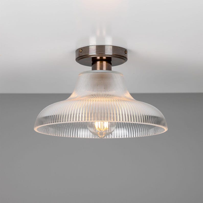 May include: A ceiling light fixture with a clear glass shade featuring a ribbed design. The fixture has a brushed nickel finish.