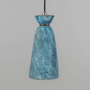 May include: A blue ceramic pendant light with a textured finish. The light has a metal ring around the top.